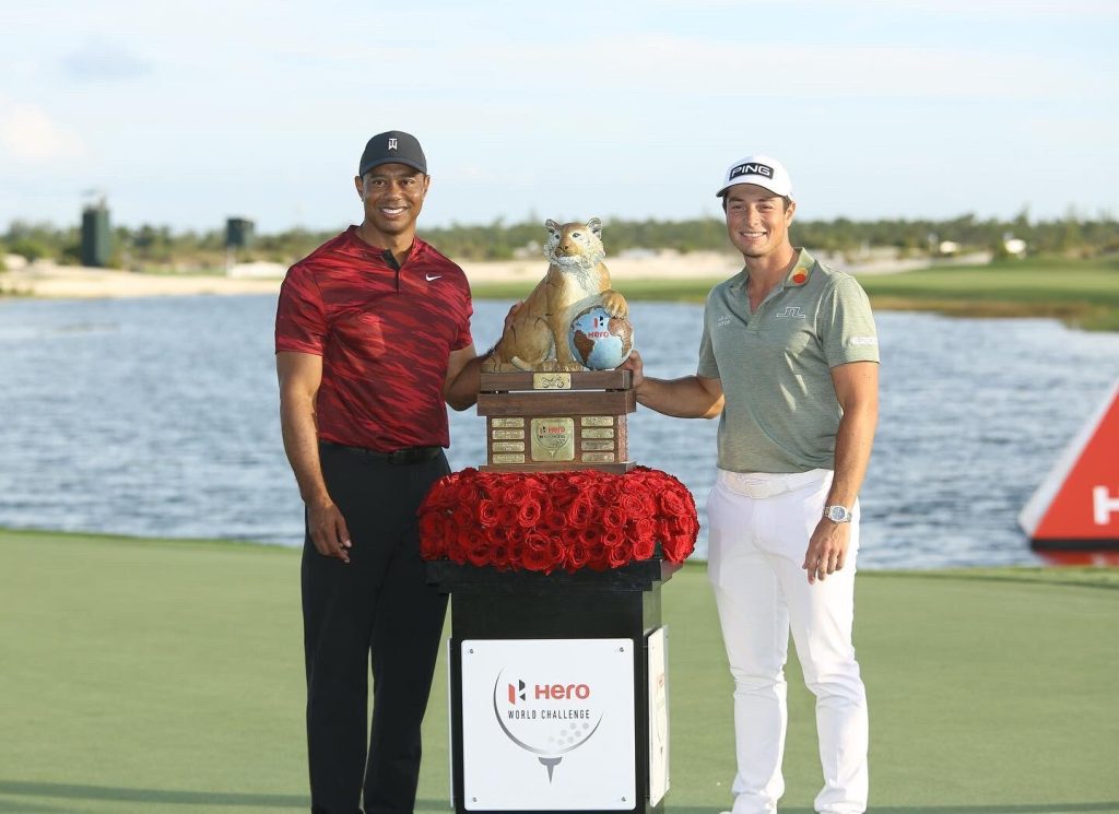 Tiger Woods handing over the winning trophy to Viktor Hovland